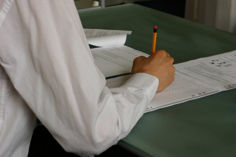 Gros plan sur une main d'élève écrivant sur sa copie d'examen, illustration du calcul de moyenne au brevet