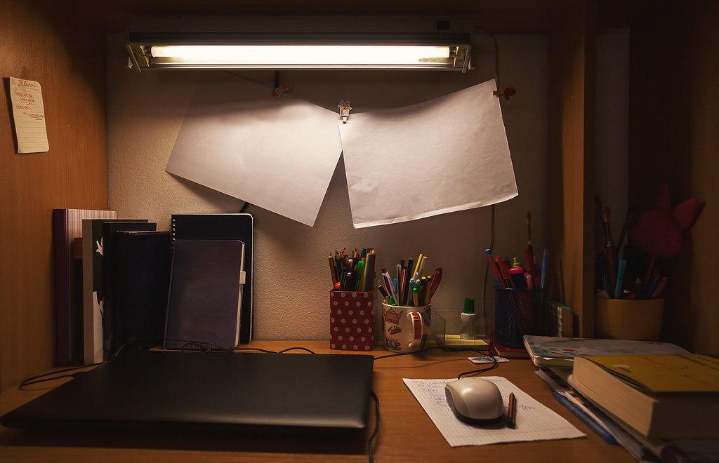 Bureau d'étudiant avec ordinateur, cahiers et lampe, pour calculer sa moyenne générale annuelle