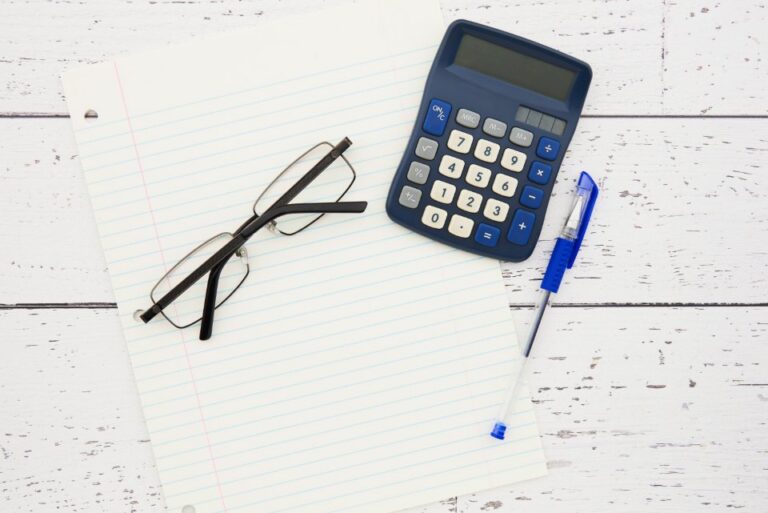 Calculatrice, lunettes et stylo sur une feuille lignée, pour calculer sa moyenne BTS par unité