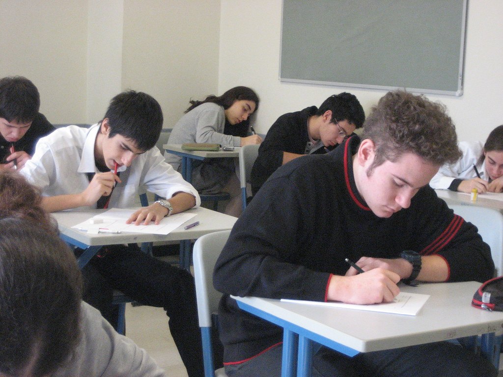 Élèves en salle d'examen écrivant leur copie, pour calculer sa moyenne au brevet 2026 selon la formule officielle
