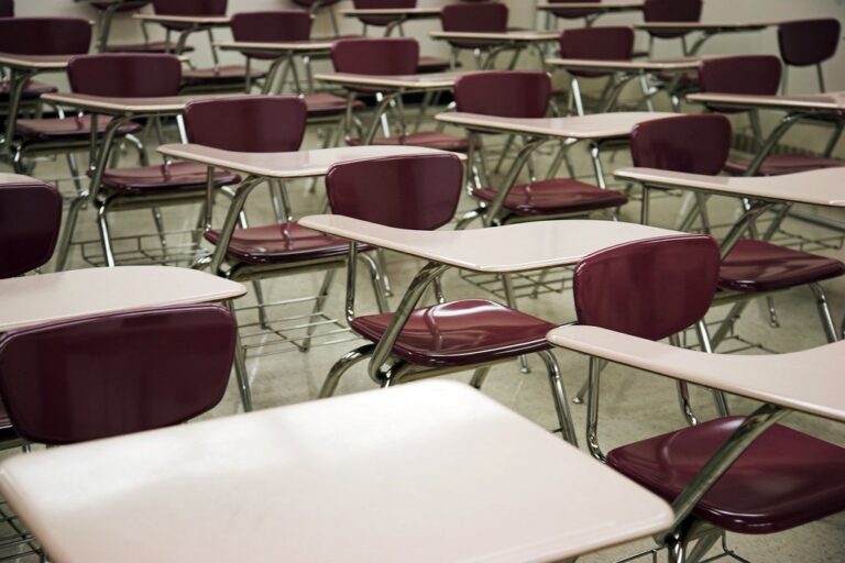 Salle d'examen avec tables vides en rangées, pour calculer sa moyenne avec le contrôle continu au bac