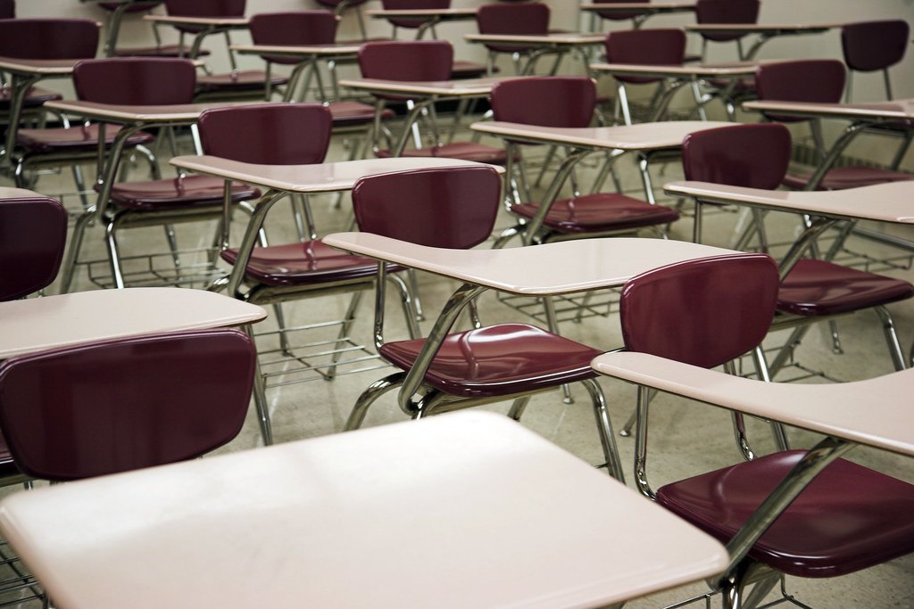Salle d'examen avec tables vides en rangées, pour calculer sa moyenne avec le contrôle continu au bac